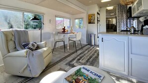 A cozy RV interior with a dining area, a kitchen, and a living space. - 2 separate RV’s with queen-sized beds, dining area, and full kitchen. (Talent)