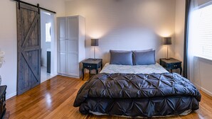 Un dormitorio con una cama grande, dos mesitas de noche, un armario y una puerta corredera tipo granero.