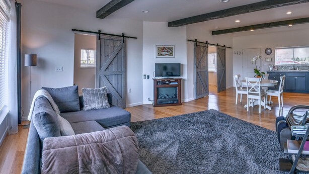Una sala de estar moderna con un sofá modular, una chimenea y un comedor con una cocina al fondo.
