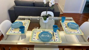 A dining table set with blue plates, cups, and cutlery, surrounded by white chairs. - CasaMia tra Navigli e Università (Milano)