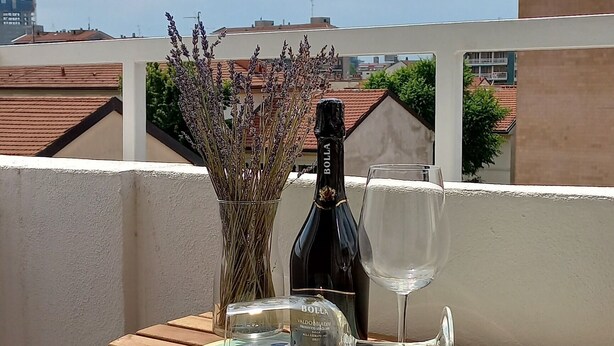 A wooden table with a bottle and a wine glass on a balcony. - CasaMia tra Navigli e Università (Milano)