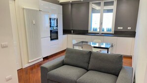 A modern kitchen with white cabinets, a built-in oven, and a window above the sink. - CasaMia tra Navigli e Università (Milano)