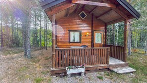 Une cabane en bois avec une véranda, deux portes et une petite fenêtre.