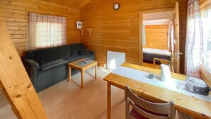Une cabane confortable avec un canapé, une petite table, une chaise et un lit avec un matelas.