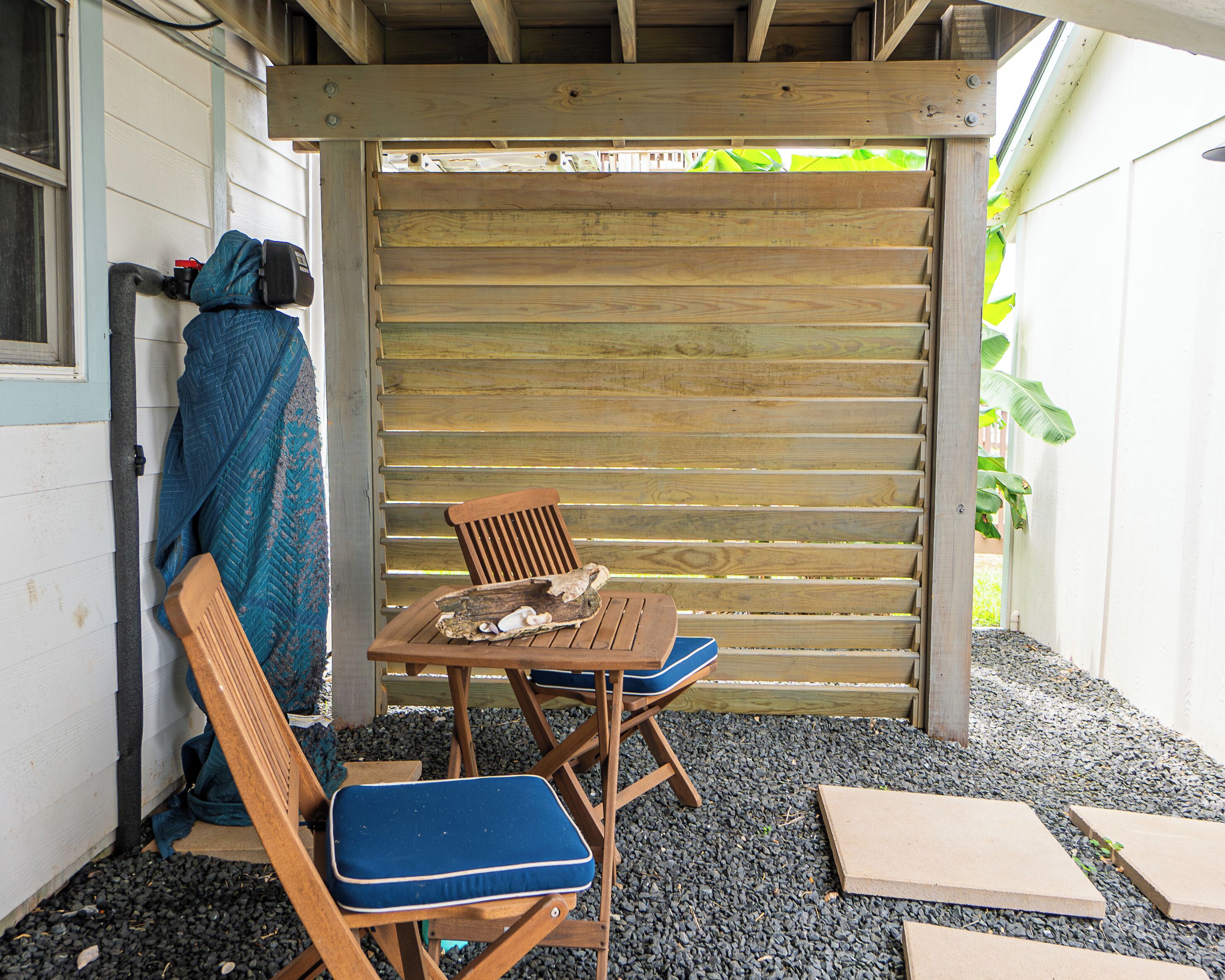 A wooden outdoor seating area with a table and two chairs, a covered bench, and a wooden fence.