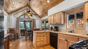 A kitchen with wooden cabinets, a stove, and a dining area with chairs and a table.