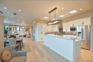 A modern kitchen with white cabinetry, a large island, stainless steel appliances, and recessed ceiling lighting. - 2 bedrooms, office with sofa bed, sofa bed in living room, 3 bathrooms (Ashland)