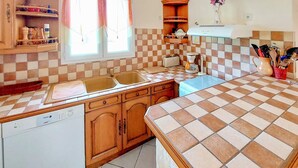 Een keuken met houten kastjes, een vaatwasser, een spoelbak en een betegelde spatwand.