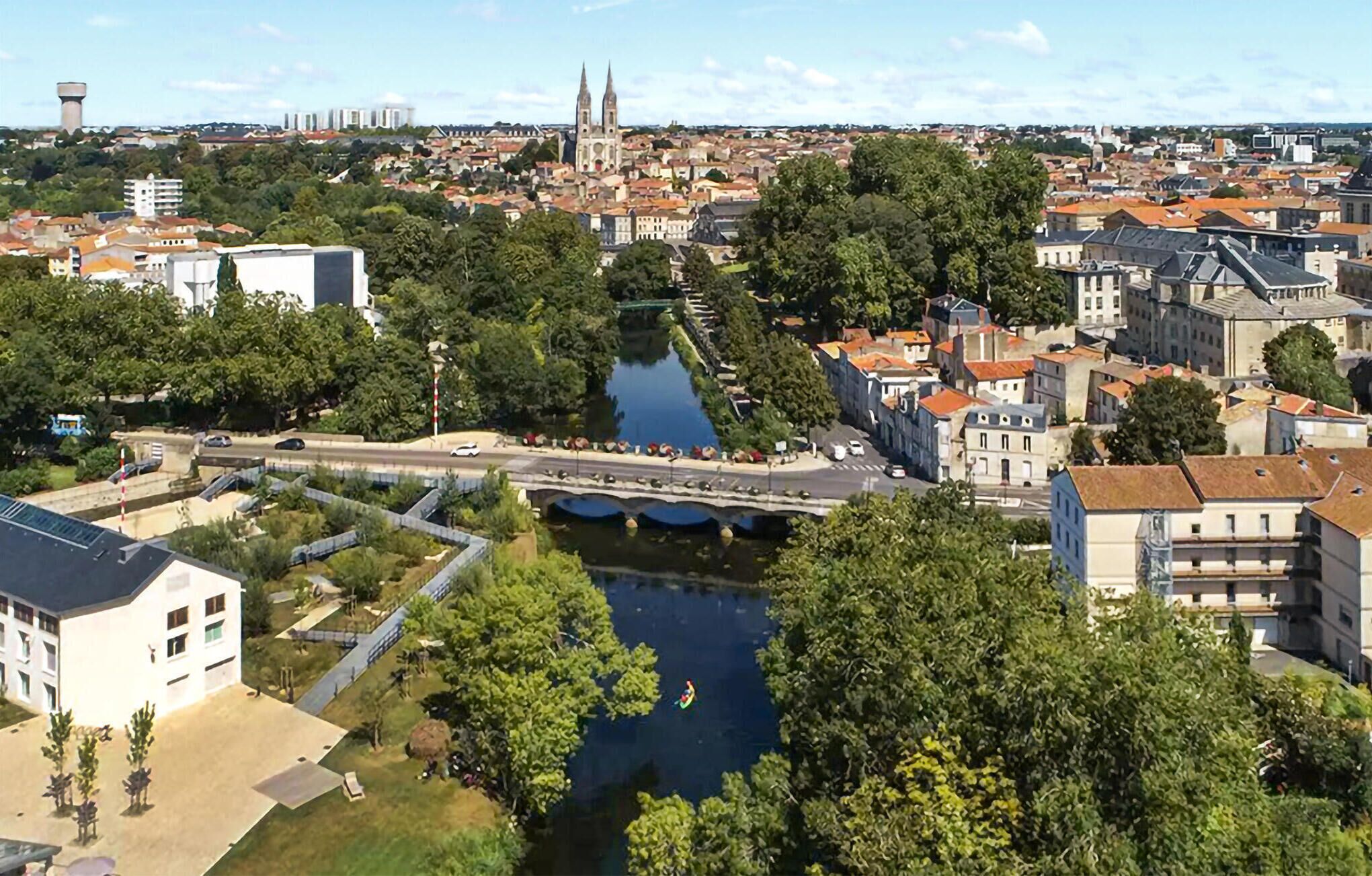 Une vue sur la ville, depuis la rive, avec un pont, des bâtiments historiques et un clocher d’église imposant.