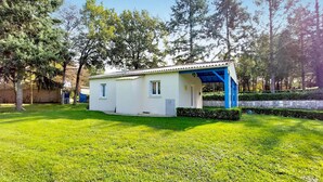 Een laag, wit gebouw met een blauw dak, omgeven door een verzorgd gazon en bomen.