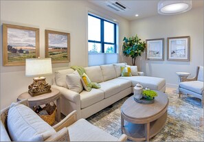 Una sala de estar con un sofá modular, una mesa de centro redonda y un ventanal con persianas.