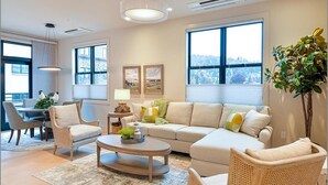 Un salon moderne comprenant un canapé, des fauteuils, une table basse et un coin repas avec une table et des chaises.