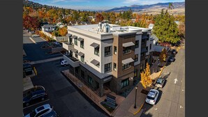 Un immeuble à plusieurs étages, doté d’un toit plat, d’un parking et offrant une vue sur un paysage vallonné.