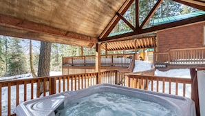Een hottub in een houten chalet met uitzicht op een besneeuwde boss.