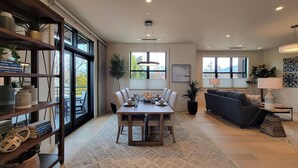 Una sala moderna con comedor, ventanas amplias y una estantería.
