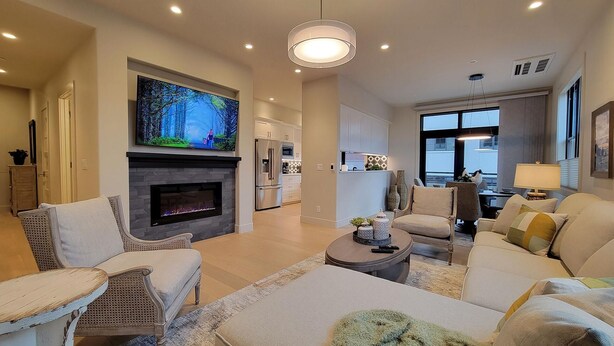 Una sala de estar moderna con chimenea, asientos cómodos, un televisor de pantalla plana y vistas a la cocina.