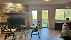 A living room with a stone fireplace, two black chairs, a sofa, and a large window with a view. - Breathtaking mountain views-4king en suites, bunk rm, sauna, air hockey,MANCAVE! (Hot Springs Village)