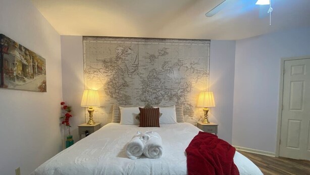A hotel room with a large bed, two bedside lamps, a map on the wall, and a red throw blanket. - Breathtaking mountain views-4king en suites, bunk rm, sauna, air hockey,MANCAVE! (Hot Springs Village)