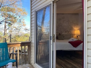 Une chambre avec un lit, une carte accrochée au mur et une vue sur les arbres à l’extérieur.