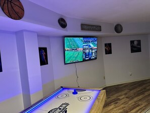 Ein Zimmer mit Fernseher, der an der Wand befestigt ist, einem Billardtisch und sportlicher Dekoration.