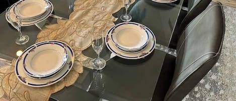 A dining table set for six with black chairs, a decorative table runner, and a vase with blue flowers.
