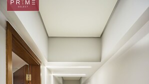 A modern hallway with a wooden door on the left, a ceiling light, and a tiled floor. - Prime Select Kattameya Bavaria (Cairo)