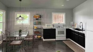 Une cuisine équipée d’un ventilateur de plafond, d’une table à manger avec des chaises, d’un four à micro-ondes, d’un four traditionnel et d’un évier.