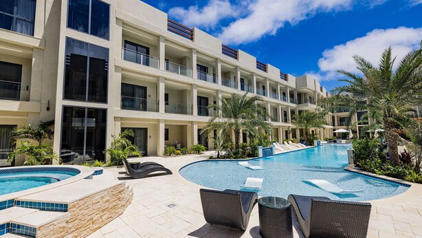 A hotel with a pool, outdoor seating, and palm trees. - Wariruri 2-13 BRAND NEW Apartment, private balcony! (Noord)
