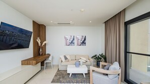 A modern living room with a flat-screen TV, a sofa, a coffee table, and a large window. - Wariruri 2-13 BRAND NEW Apartment, private balcony! (Noord)