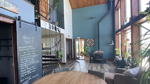 A spacious indoor area with a wooden ceiling, a large round table, and several seating options.
