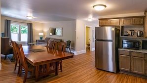 A modern kitchen with a stainless steel refrigerator, wooden cabinets, and a dining area with a wooden table and chairs. - Spacious 2 bedroom historic home with two king beds and kitchenette. (Ashland)