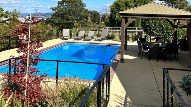 Piscina con sillones de descanso y una zona de estar cubierta.