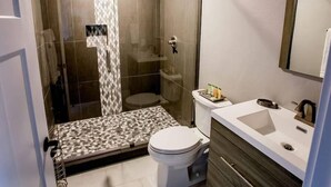 Un baño moderno con ducha de vidrio, inodoro y tocador con espejo.