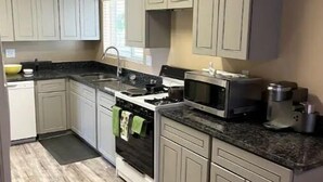 A kitchen with light gray cabinets, a black stove, a microwave, and a coffee maker. - Enjoy living on a pecan orchard surrounded by trees!!!!!!
 (Las Cruces)