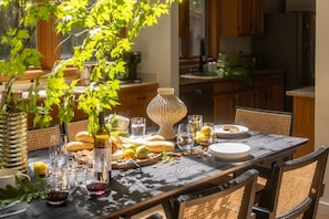A dining table set with plates, glasses, and a bottle, surrounded by chairs and a vase.