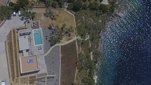 Vista aérea de una propiedad costera con piscina, terraza cubierta y costa rocosa.