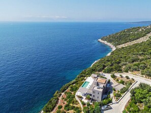 A coastal property with a swimming pool, a modern house, and a view of the sea.