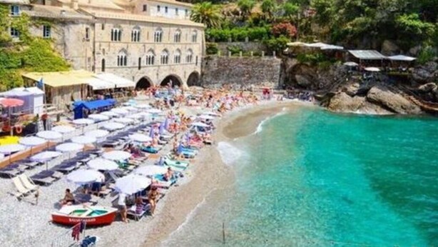 A coastal building with a dome and arched windows, a beach with umbrellas and people, and a mountainous backdrop. - Apartment in Recco with 1 bedrooms sleeps 4 (Recco)