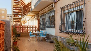 Eine Terrasse mit Tisch und Stühlen, ein Holzzaun und Kübelpflanzen.