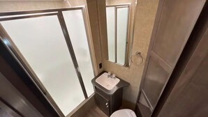 Ein kleines Badezimmer mit Dusche, Waschbecken und Toilette.
