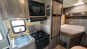 Eine kleine Küchenzeile in einem Wohnmobil, mit Herd, Spüle, Mikrowelle und Kühlschrank.