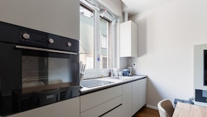 A compact kitchen with a built-in oven, a sink, and a window. - GuestHost - Modern and welcoming 80m2 apartment, ideal for 4 people, located on the mezzanine floor of a building (NO lift) in the Bullona area. The property is located in a strategic area, a few minutes walk from the “Gerusalemme” and “Domodossola (Milano)