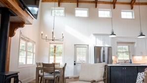 A spacious living room with a fireplace, wooden furniture, and a large window. - Farmhouse Retreat•Private Pool•Small Weddings•Hot Tub•Fire Pit•Sauna•15 Acres (Summerville)