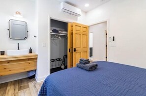 A bedroom with a bed, a wooden dresser, a mirror, and a closet with a door open. - Farmhouse Retreat•Private Pool•Small Weddings•Hot Tub•Fire Pit•Sauna•15 Acres (Summerville)