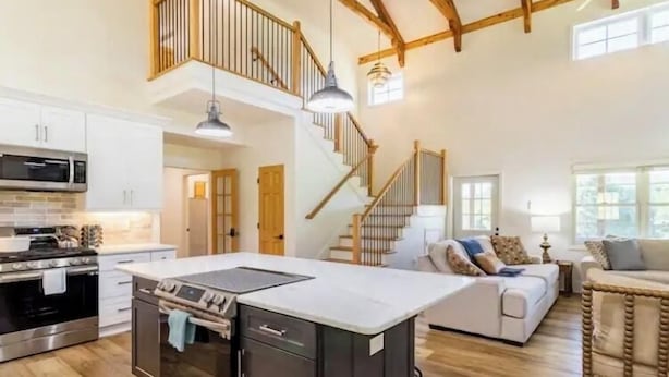 A spacious kitchen with a central island, a dining area with a table and chairs, and a staircase leading to an upper level. - Farmhouse Retreat•Private Pool•Small Weddings•Hot Tub•Fire Pit•Sauna•15 Acres (Summerville)