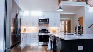 A modern kitchen with stainless steel appliances, white cabinets, and a wooden floor. - Farmhouse Retreat•Private Pool•Small Weddings•Hot Tub•Fire Pit•Sauna•15 Acres (Summerville)