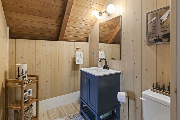 Ein Badezimmer in einer Holzhütte mit einem eingebauten Waschbecken, einem Spiegel und einer Toilette.