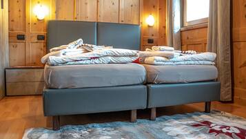 A double bed with a grey headboard, two bedside tables, and a wooden wall with built-in lighting.