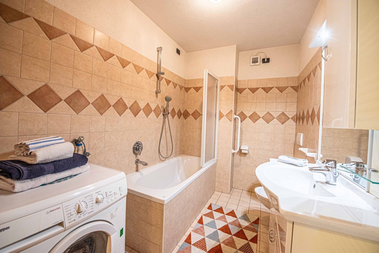 Ein Badezimmer mit Waschmaschine, Badewanne und Dusche.