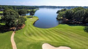 Un parcours de golf avec un obstacle d’eau, des arbres et un ciel dégagé.